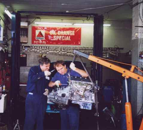 Two mechanics working together on an engine inside the shop