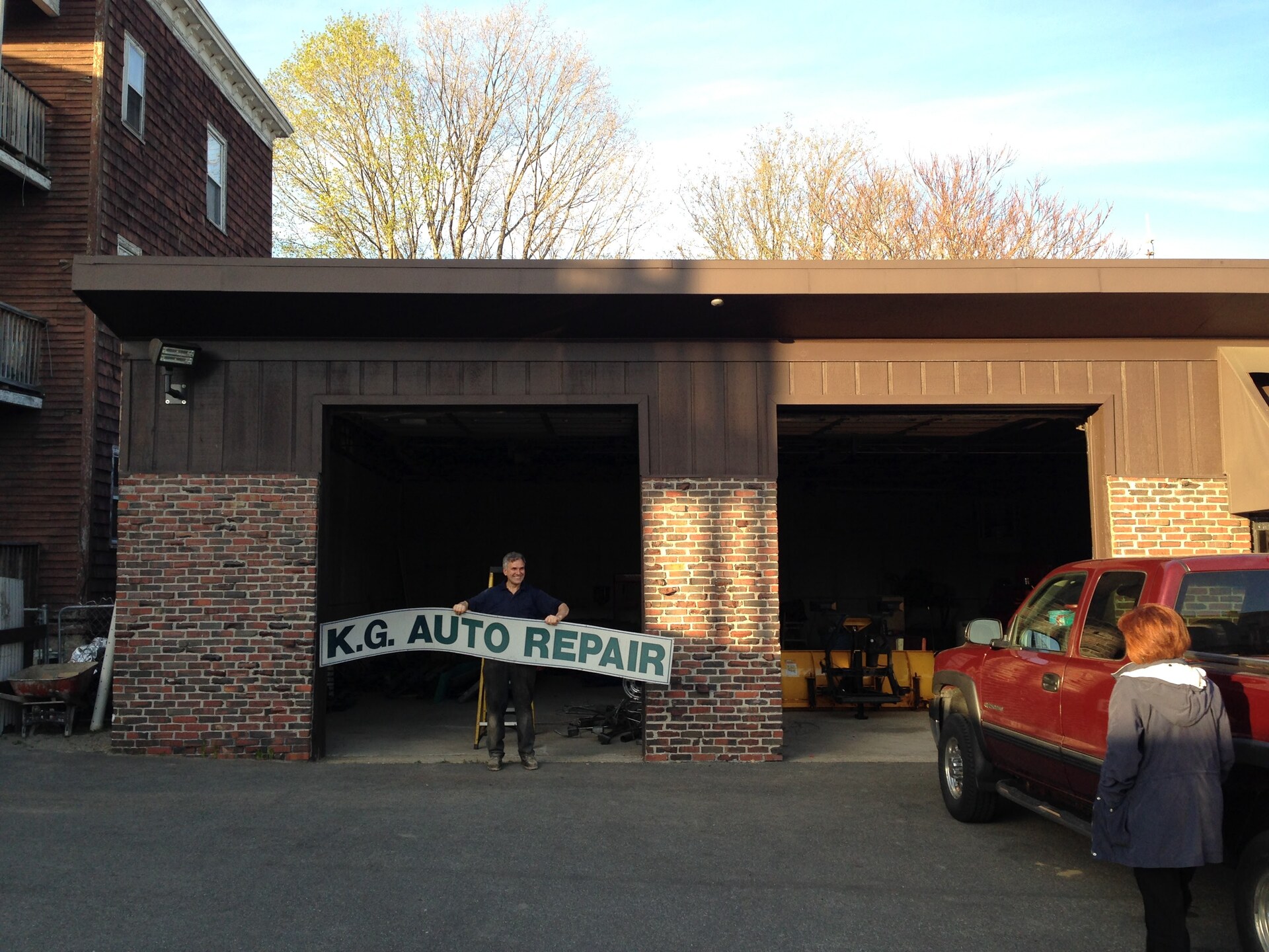 KG Auto Repair shop exterior with a person holding the shop sign